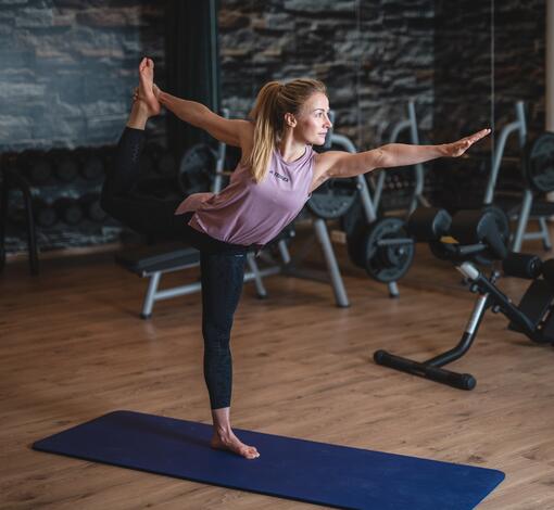 Frau macht Yoga auf einer blauen Matte in einem Fitnessstudio