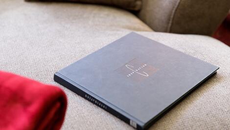 Book titled Inspiration lies on a beige sofa next to a red garment