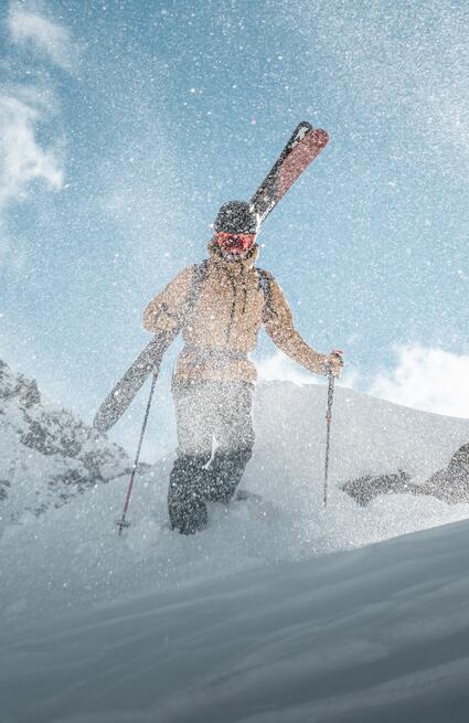 Skier with skis on his shoulder trudges through the snow