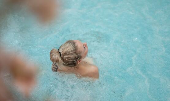 Frau mit Dutt im hellblauen Wasser, Blick nach oben