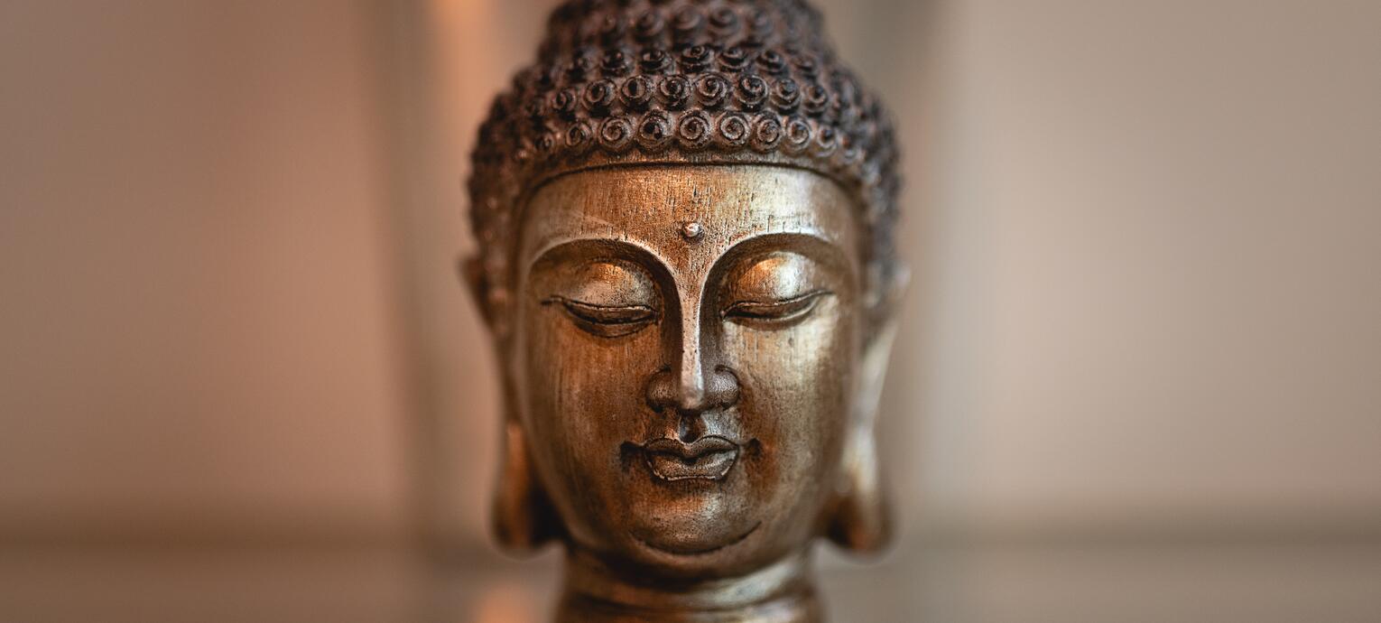 Buddha-Kopf aus Bronze mit geschlossenen Augen auf einem Glastisch