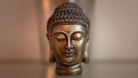 Bronze Buddha head with closed eyes on a glass table