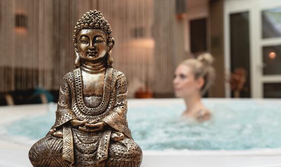 Buddha-Statue vor Whirlpool mit Frau im DAS VIER Pitztal Tirol