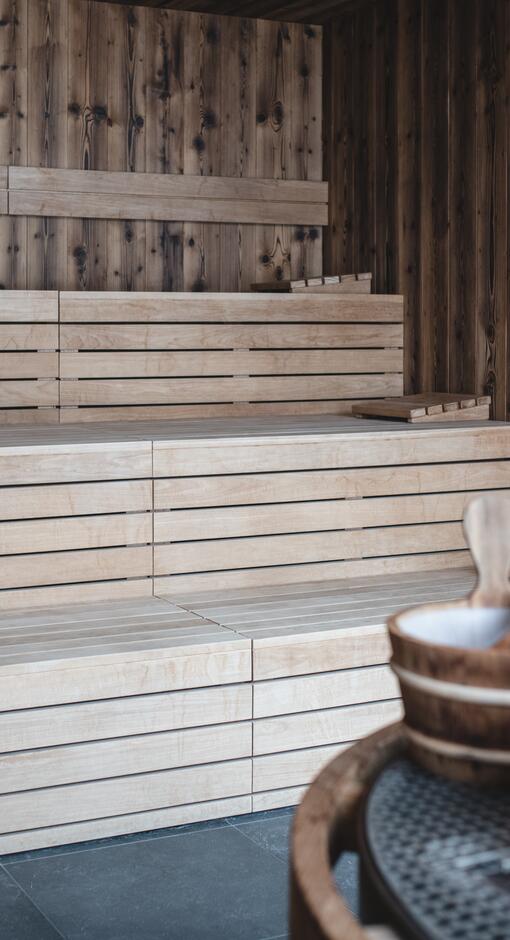 Holzsauna mit Bänken, Holzeimer und Kelle im DAS VIER – Sport- & Wellnesshotel Pitztal Tirol