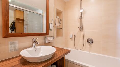 Bathroom with sink on wooden countertop, mirror, bathtub and shower