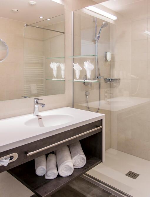 Modernes Badezimmer mit Waschbecken, Spiegel, Dusche und Handtüchern