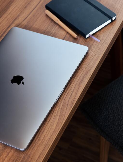 Laptop, notebook and pen on a wooden table